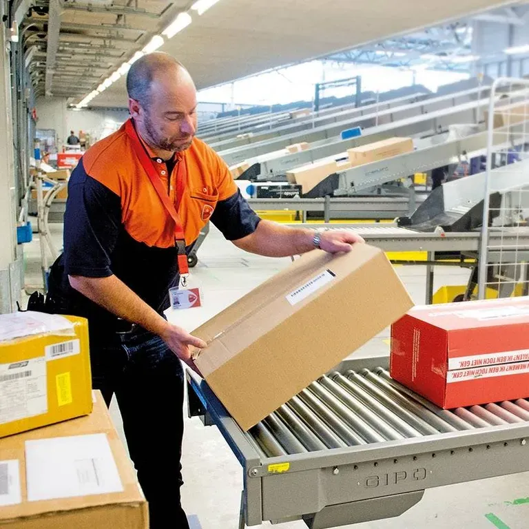 Sorteermedewerker haalt pakket van de lopende band PostNL