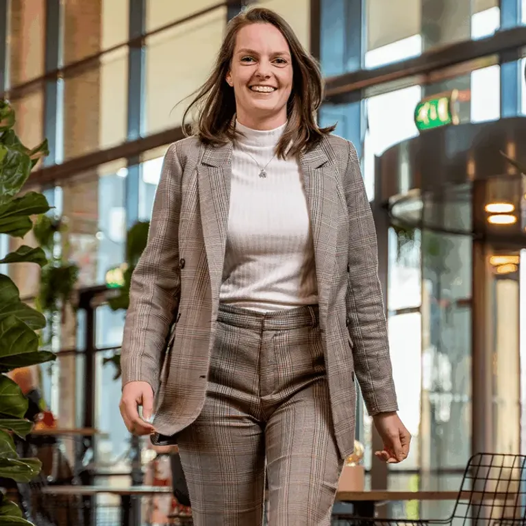 Vrouw in pak loopt recht de camera in