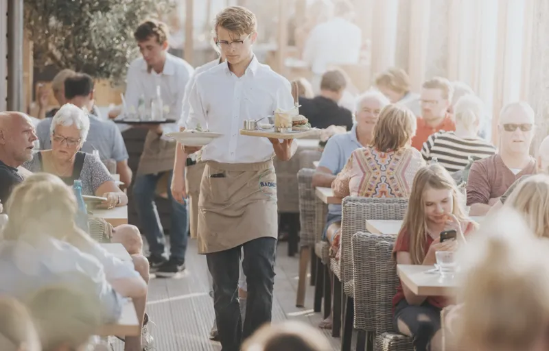 Badhuys bedieningsmedewerker met in twee handen een bord